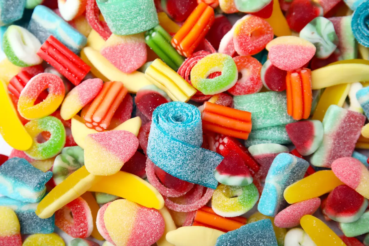 GettyImages-1490797933 A pile of assorted colorful gummy and jelly candies, including rings, belts, and fruit shapes, coated with sugar crystals.