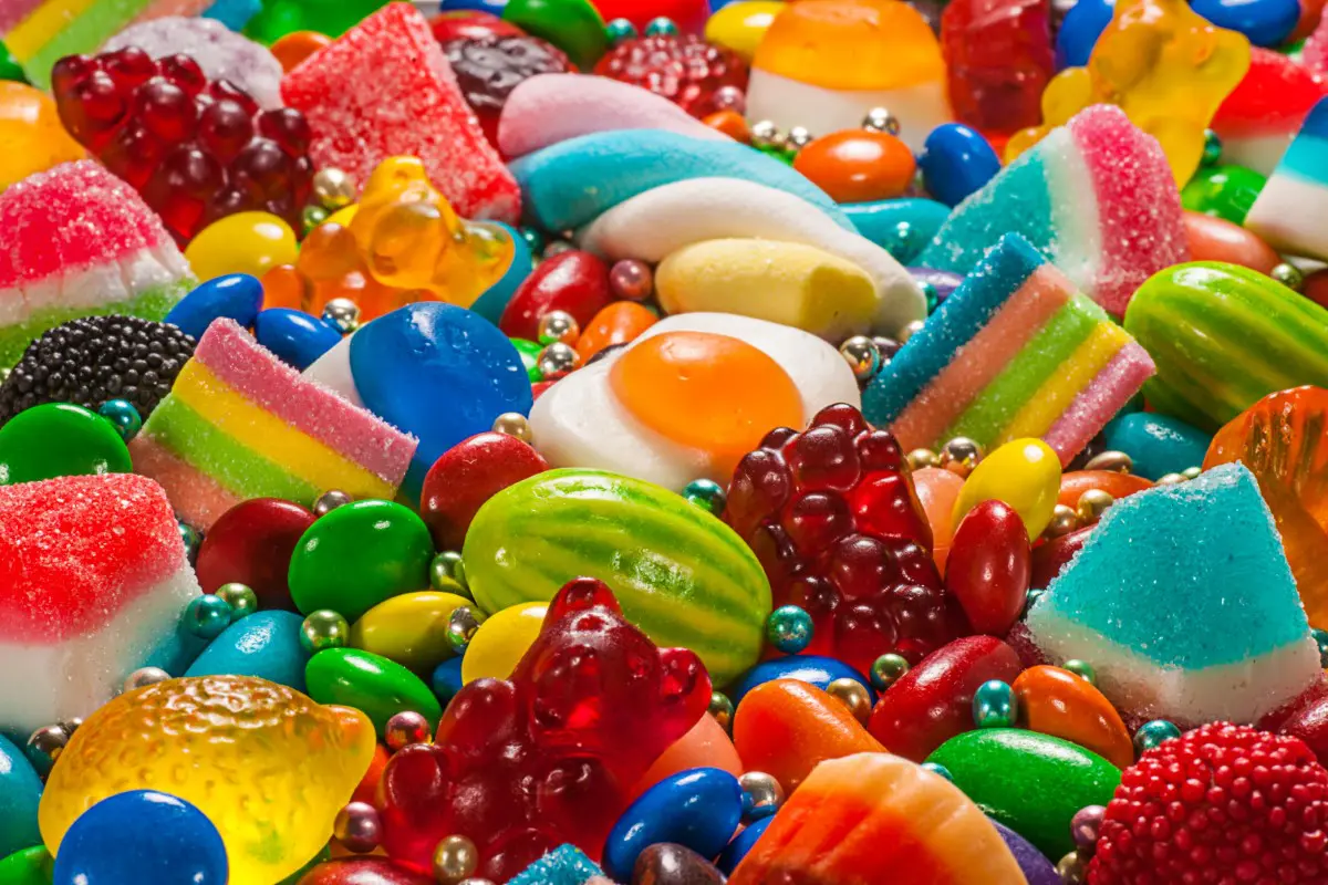 A colorful assortment of various candies, including gummy bears, jelly beans, and licorice, displayed closely together.